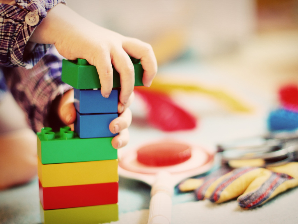 A toddler playing with colourful Duplo bricks