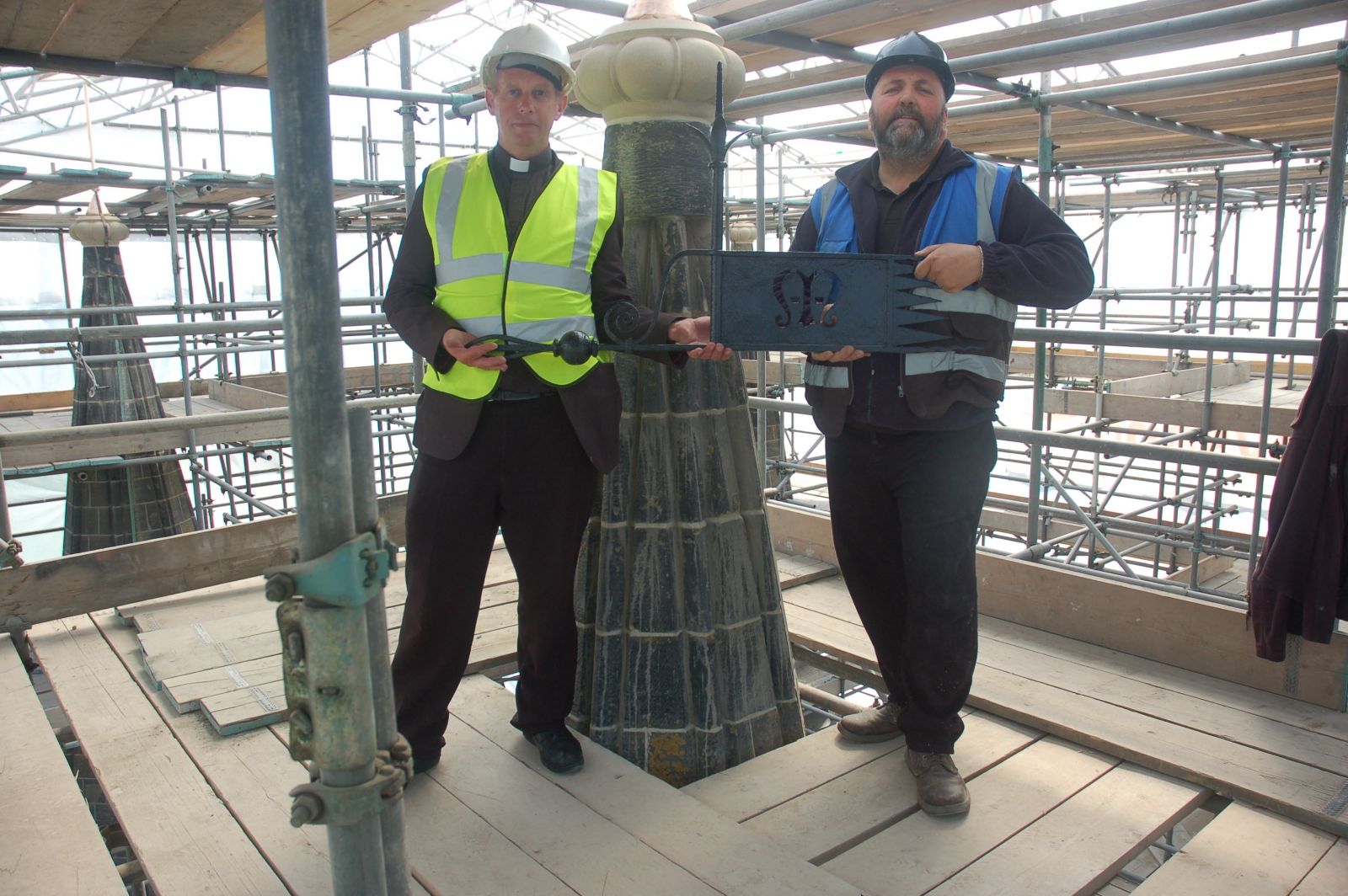 Revd Hugh Baker and Barry Firth placing the weather vane on top of one of the Tower's pinnacles