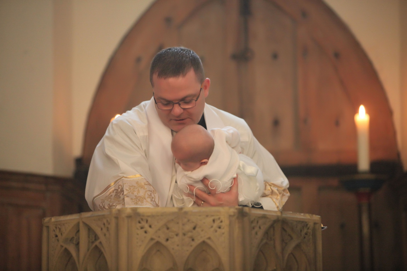 Fr Darren baptising a baby in his church